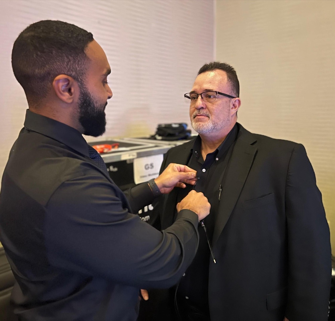 a man in a suit and glasses is getting mic'd up